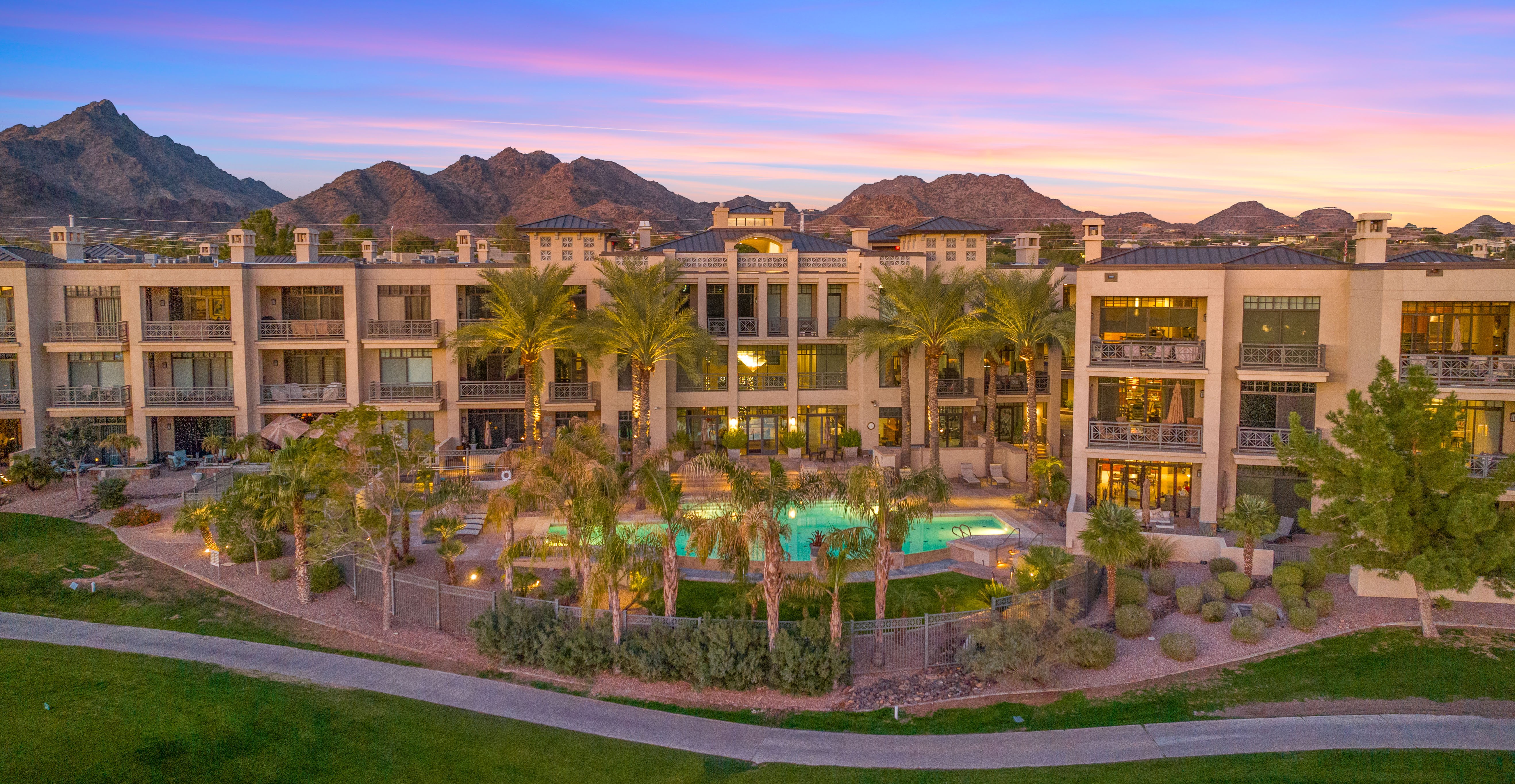 Twilight view of a Biltmore-area condo complex with pool courtyard beneath Camelback Mountain