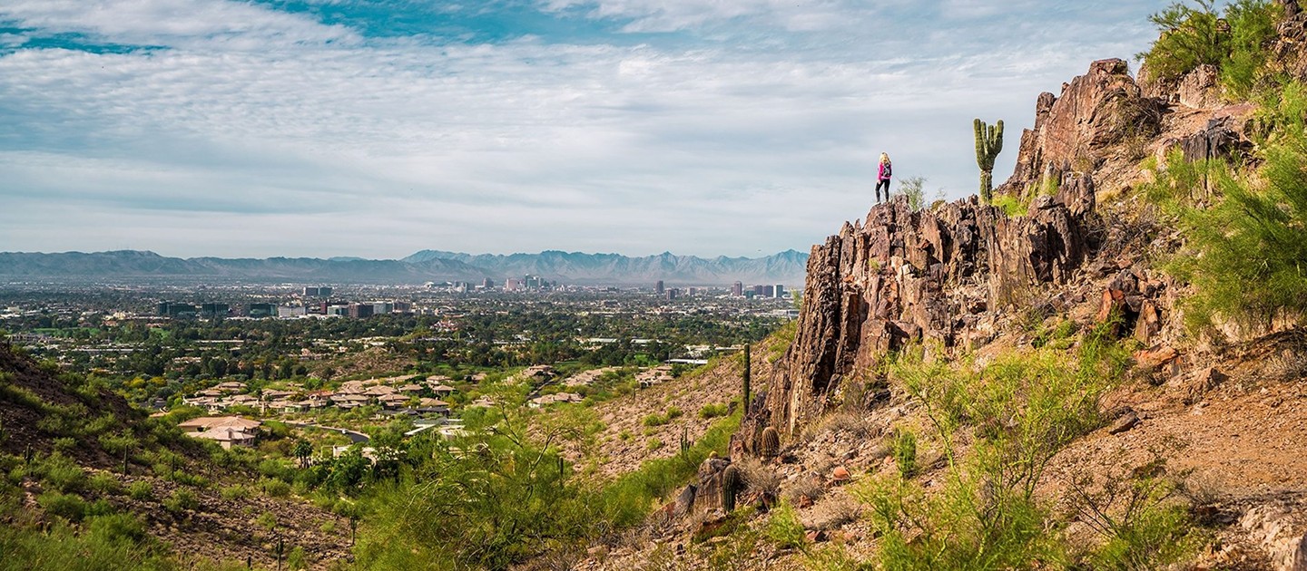 Hiker overlooking the Phoenix skyline from a Phoenix Mountain Preserve trail near Shea-Tatum